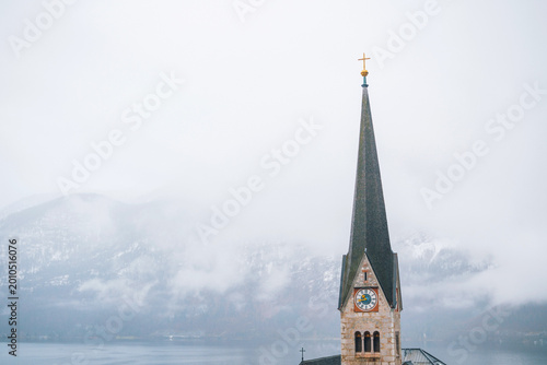 Foto Hallstatt church spire with clock standing by foggy lake mountains