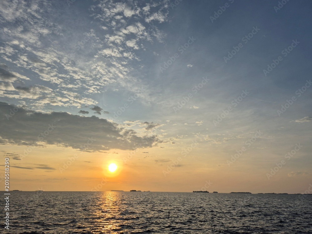 Fototapeta premium Peaceful ocean sunset with vibrant clouds and serene waves stretching to the horizon, capturing the beauty of nature's tranquility and golden light.