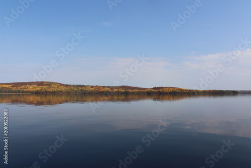 Beautiful fall colors, yellow hemlocks, whispy clouds October in Canada. Mirror image reflecting over the water Bark Lake, Madawaska Valley, Renfrew County, Ontario, Canada