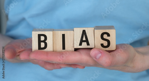 Photos Hands gently hold wooden blocks spelling BIAS