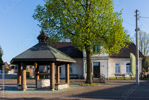 Traditional wooden well and historic building in Zloty Potok, Jura Krakowsko-Czestochowska, Poland.