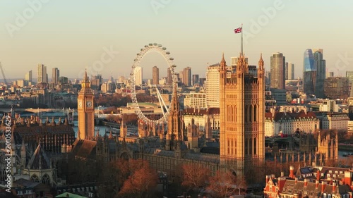 Golden hour light illuminating Palace of Westminster, iconic Big Ben, London Eye with the River Thames and central London's cityscape in the background