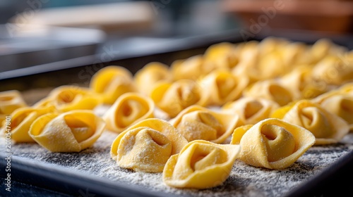 Raw tortellini filled with pasta lining a floured tray in a kitchen