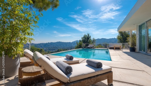 Luxury infinity swimming pool on a sunny terrace with lounge chairs and panoramic mountain views at a modern hillside villa residence during a bright summer day