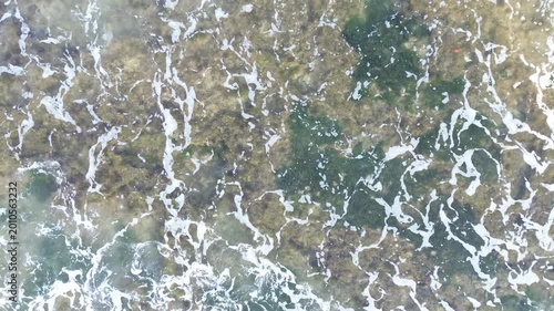 Aerial View of Foamy Ocean Waves Breaking on Rocky Coast