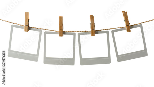 Obraz na plátně Four empty instant photo frames hanging on a clothesline with wooden pegs, isola