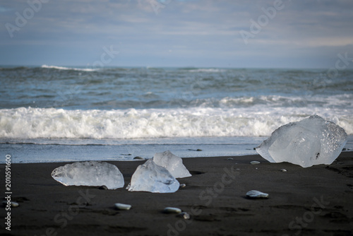 Ice chunks on black sand beach with waves