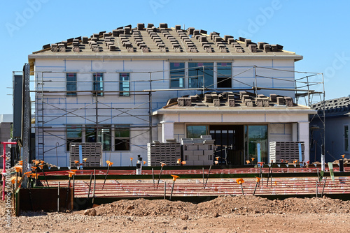 Obraz na płótnie Two-story tract home under construction with roof installation and a concrete fo