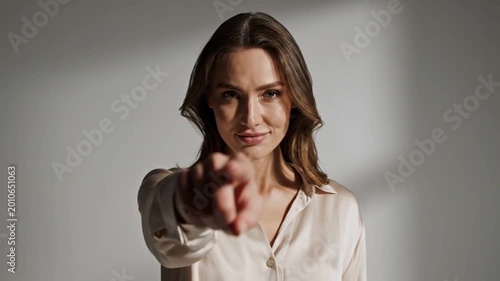 A female model smiling while pointing at the camera.