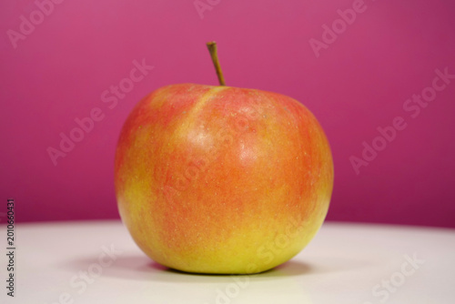 Quadro su tela Ripe red yellow fresh apple on pink background, close-up