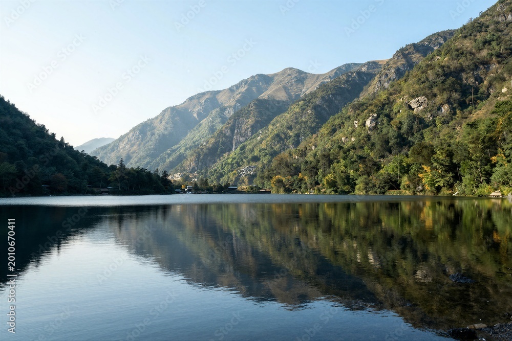 Fototapeta premium Mountain range reflected on calm lake with clear sky