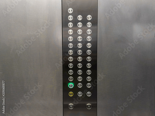 Modern elevator control panel with numerous illuminated floor buttons stainless steel surface minimalistic design vertical composition close up technology urban building navigation concept