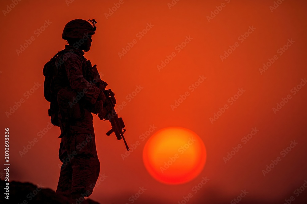 Fototapeta premium Silhouette of a soldier standing guard during a dramatic desert sunset, symbolizing duty and vigilance