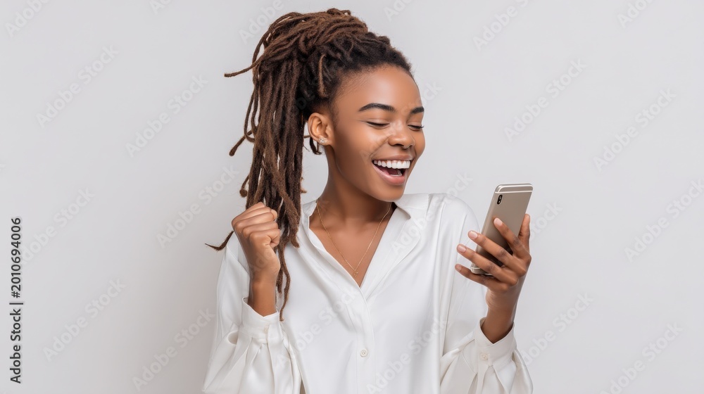 Fototapeta premium Excited young Black woman with dreadlocks celebrating success while looking at her smartphone screen with joy