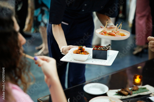 Obraz na plátně Elegant catering scene at a stylish cocktail event where a waiter serves a seafood platter to guests