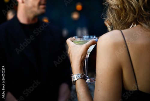 Photos Elegant woman holding a martini glass while flirting with a man in a stylish bar setting