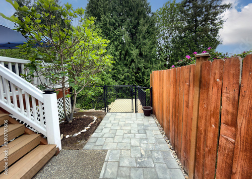 Canvastavla Stone pave pathway to lower deck of residential home with patio deck backyard an