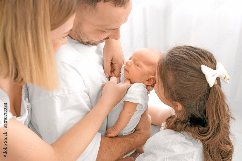 Fototapeta premium A newborn boy surrounded by loving parents. The family admires the baby, gently holding him in their arms.