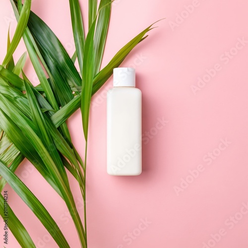 White Bottle of Lotion Resting on a Pink Background Beside Palm Leaves in Bri...