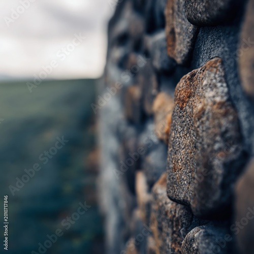 Stone Wall Stands in Focus With Blurred Field Behind It During Cloudy Day