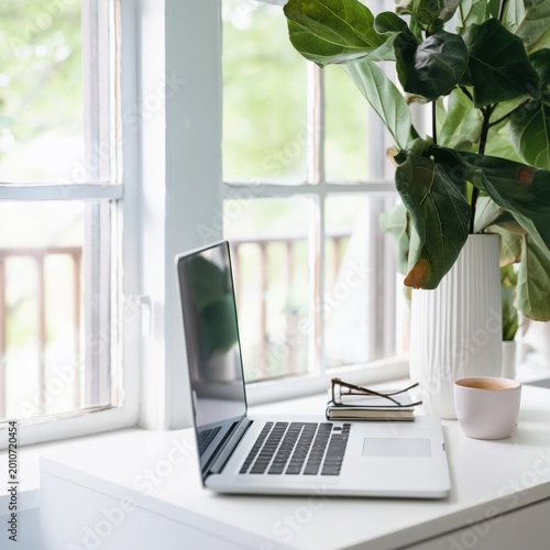 Laptop on a White Desk With Colorful Screen and Vase in a Modern Indoor Space...