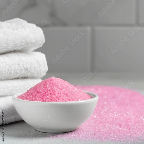 Pink Bath Salts in a Small Bowl Beside White Towels on a Counter in a Bathroom