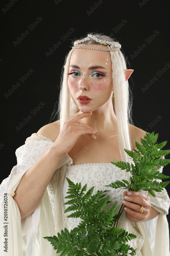 Fototapeta premium Beautiful elf girl with floral decor on black background