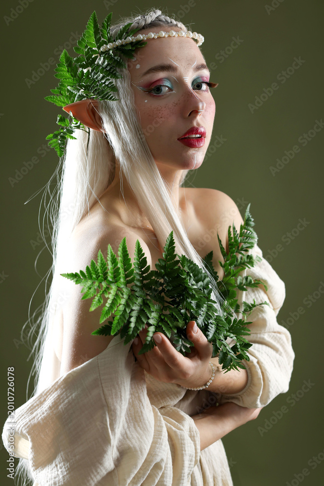 Fototapeta premium Beautiful elf girl with floral decor on dark olive background