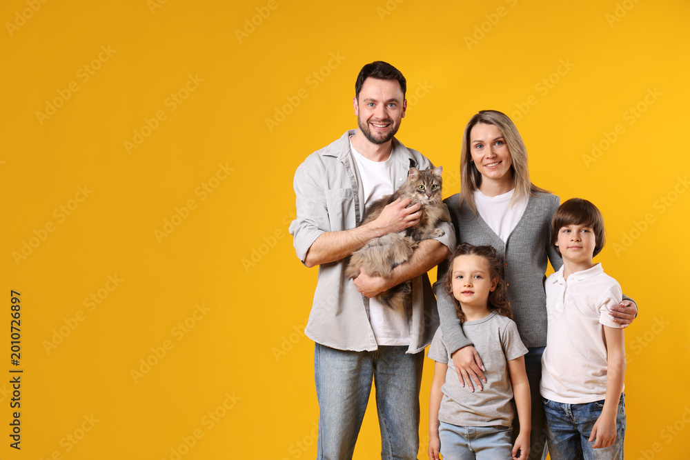 Fototapeta premium Happy family with their cute cat on orange background, space for text. Adorable pet