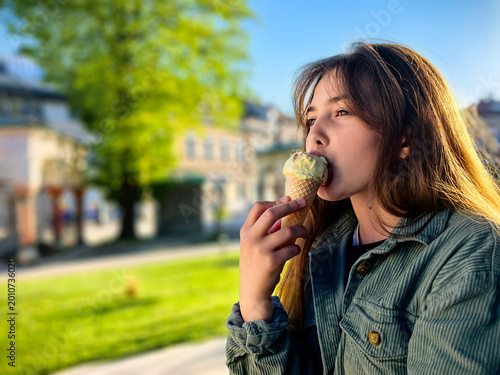 Teenage Girl Enjoying Ice Cream in a Waffle Cone Outdoors On A Sunny Day.