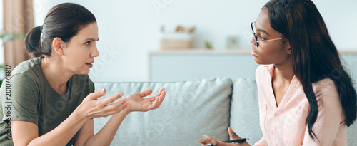 Fényképezés Two women engage in a serious conversation while seated on a sofa in a well-lit room
