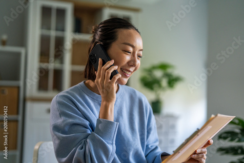 Photos Asian woman remote working from home talking on phone