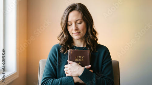 Woman holding holy bible to chest with eyes closed. Expressing faith and devotion in prayer. Spirituality and christianity concept. Copy space