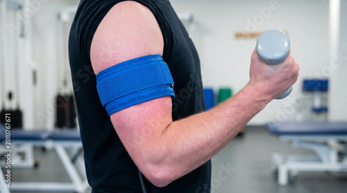 Arm lifting dumbbell with blue blood flow restriction band