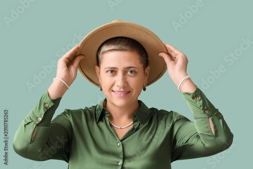 Young woman with short hair and stylish hat on green background