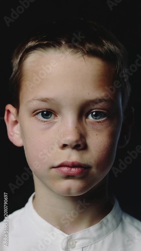 Young boy sticking out tongue against black background close up shot