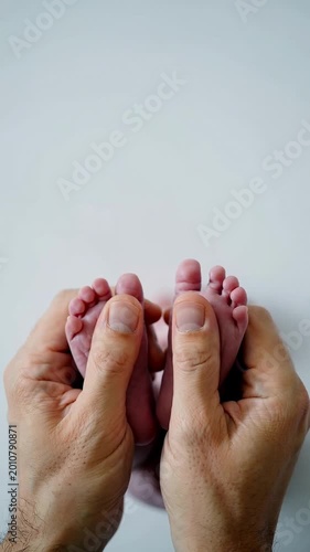 Parent holding tiny newborn baby feet against white background, extreme close up shot