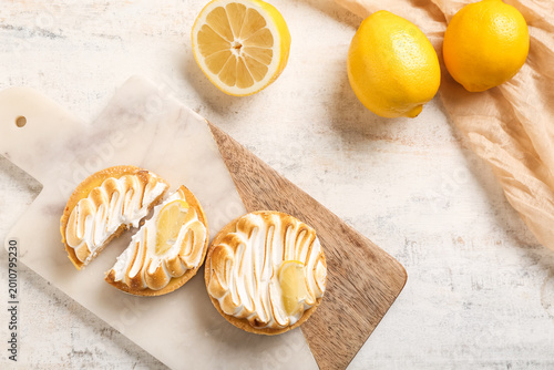 Tableau sur toile Lemon meringue tartlets with sliced tart on marble board and fresh lemons, top v