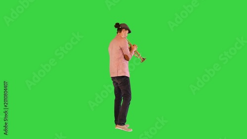 Young gifted street musician plays the trumpet masterly on a Green Screen, Chroma Key.