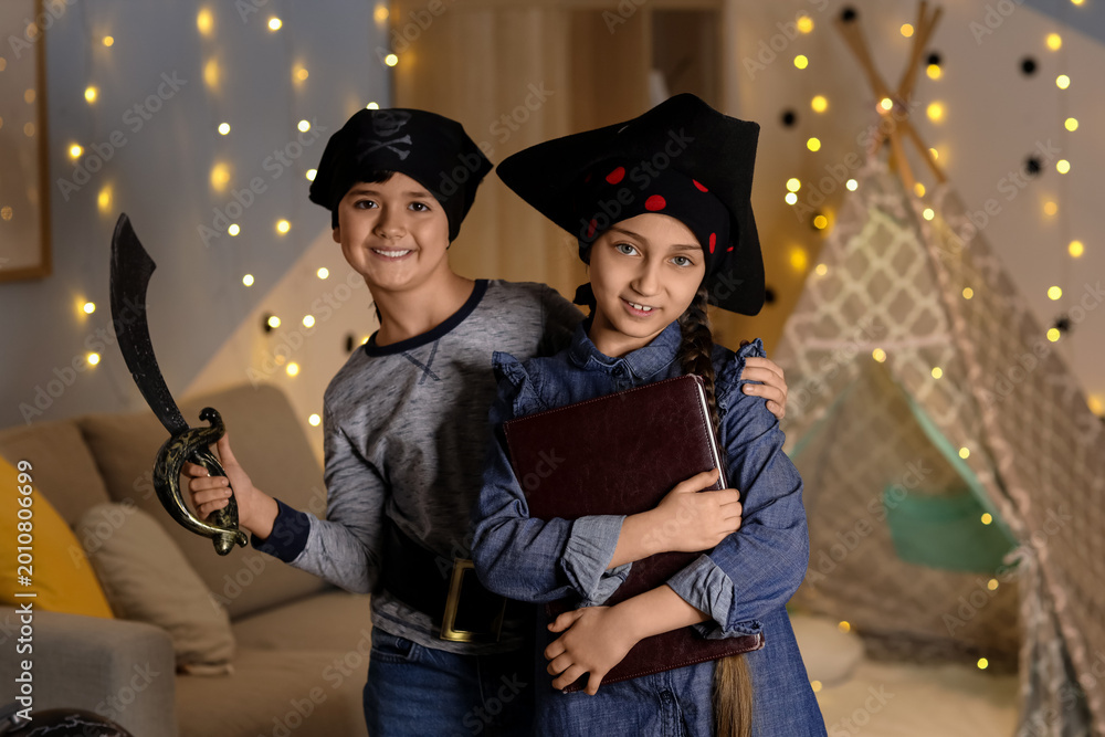 Fototapeta premium Cute children dressed as pirates with adventure book at home in evening