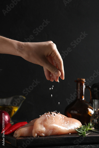 Woman salting raw chicken b...