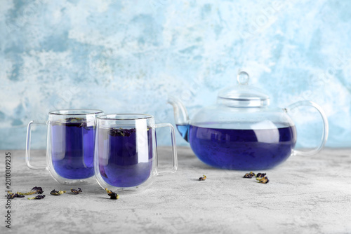 Foto Cups and teapot of butterfly pea flower tea on blue grunge background