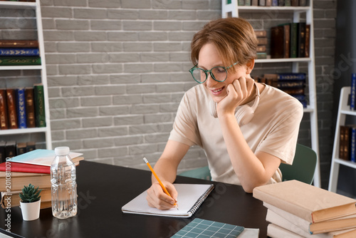 Male student studying at table in library