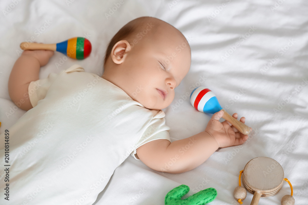 Fototapeta premium Cute baby with toys sleeping on bed, top view
