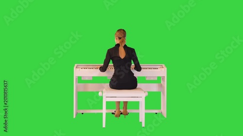 Beautiful female musician performs classical composition on the piano on a Green Screen, Chroma Key.