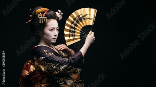 Obraz na płótnie 漆黒の静寂と優雅な日本の美。白塗りと着物姿が際立つ日本人芸者の真剣で美しいポートレート
