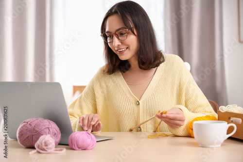 Young woman with laptop kni...