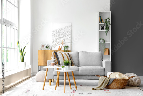 Fotografie Interior of light living room with grey sofa, coffee table and wicker basket