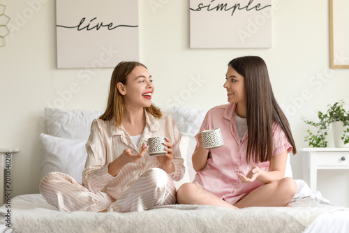 Female friends drinking coffee in bedroom