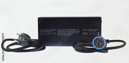 Black battery charger with coiled cord and plug. Modern design meets practical use. Ideal for product catalog or tech setup. Clean background enhances visual clarity. Simple, uncluttered presentation.